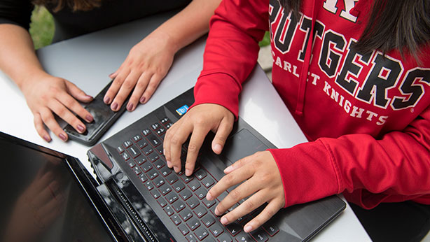 Rutgers Today Rutgers Today, Rutgers news - Office of Financial Aid, student in Rutgers sweatshirt types on laptop