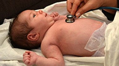 Image of newborn being examined by midwife